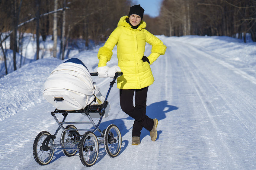 Woman on snowy road with baby stroller