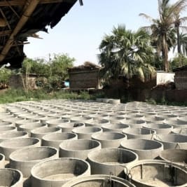 rows of cement pit toilet rings in India