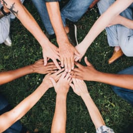 circle of people with hands meeting in middle