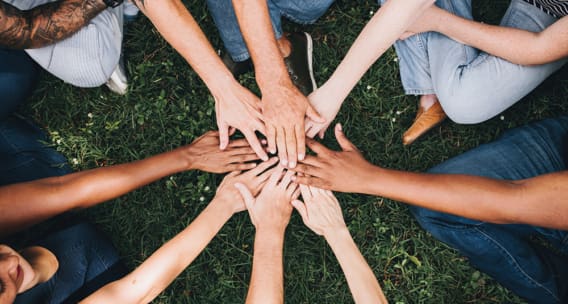 circle of people with hands meeting in middle