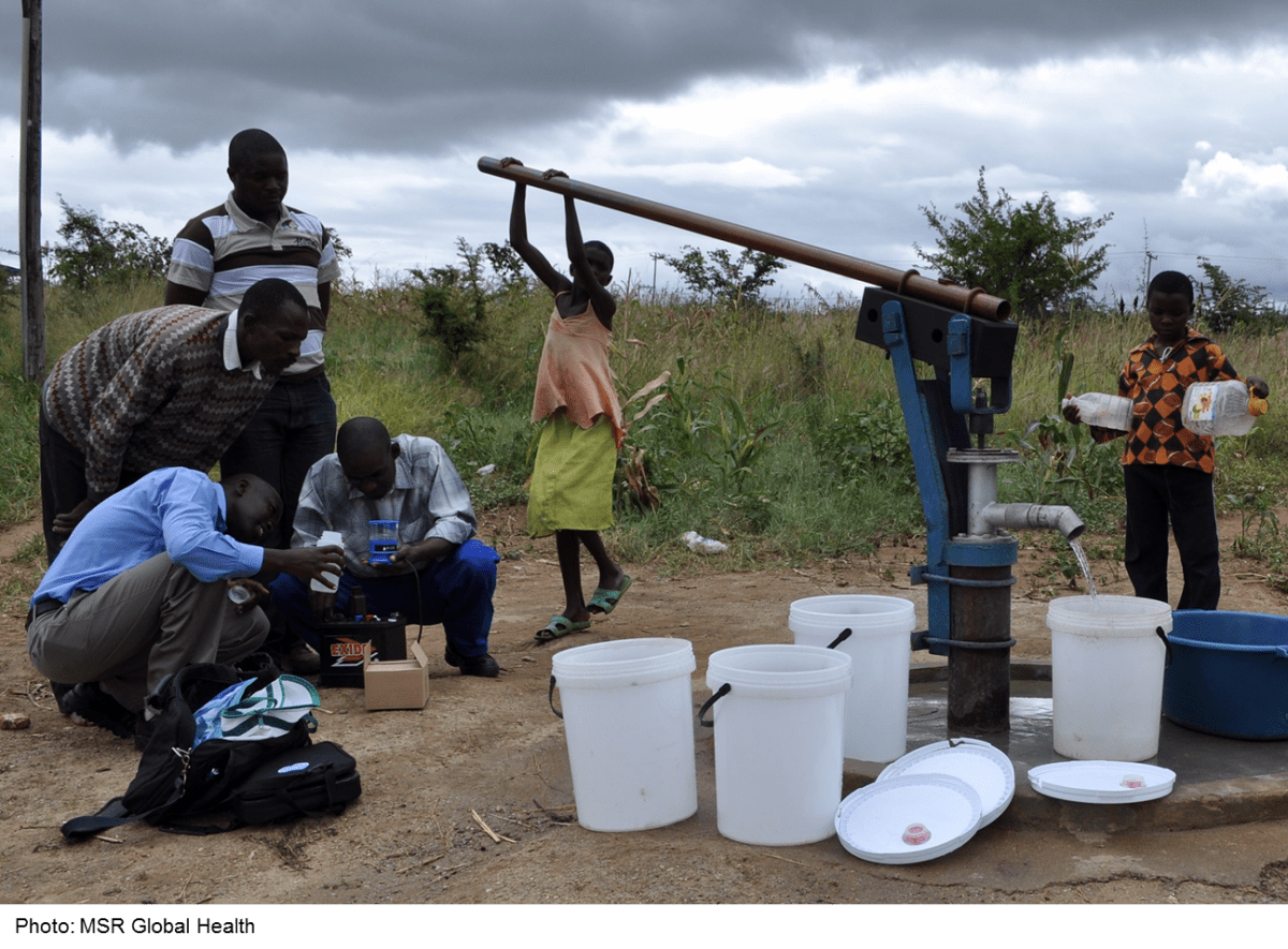 children pumping water and adults testing water