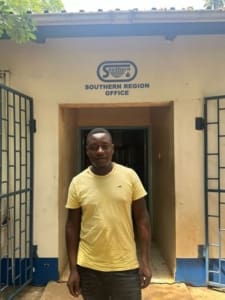 Man in yellow t shirt standing in front of Southern Region Office building