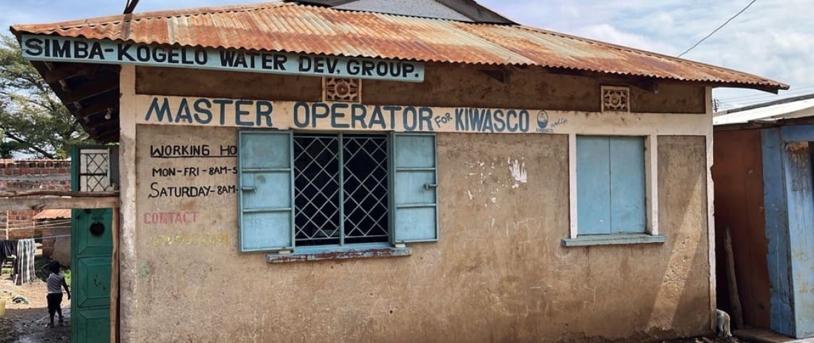 Single story building with sign reading Simba-Kongelo Water Dev. Group